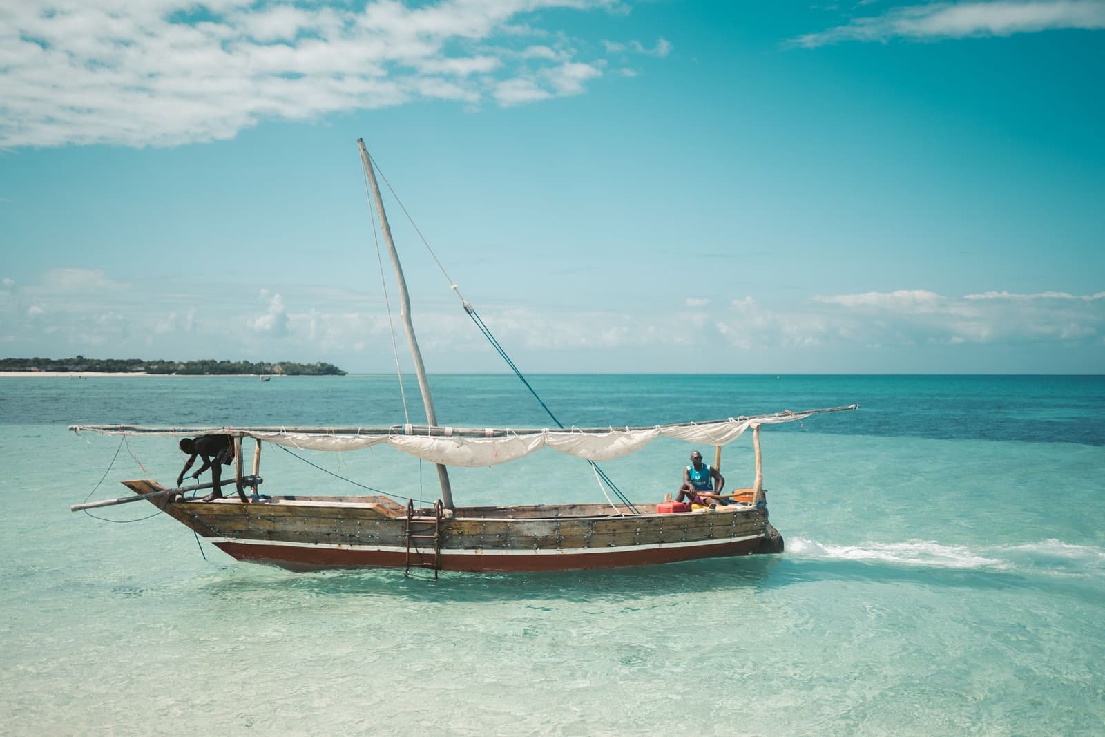 Traditional dhow boat anchored in clear turquoise water near Zanzibar