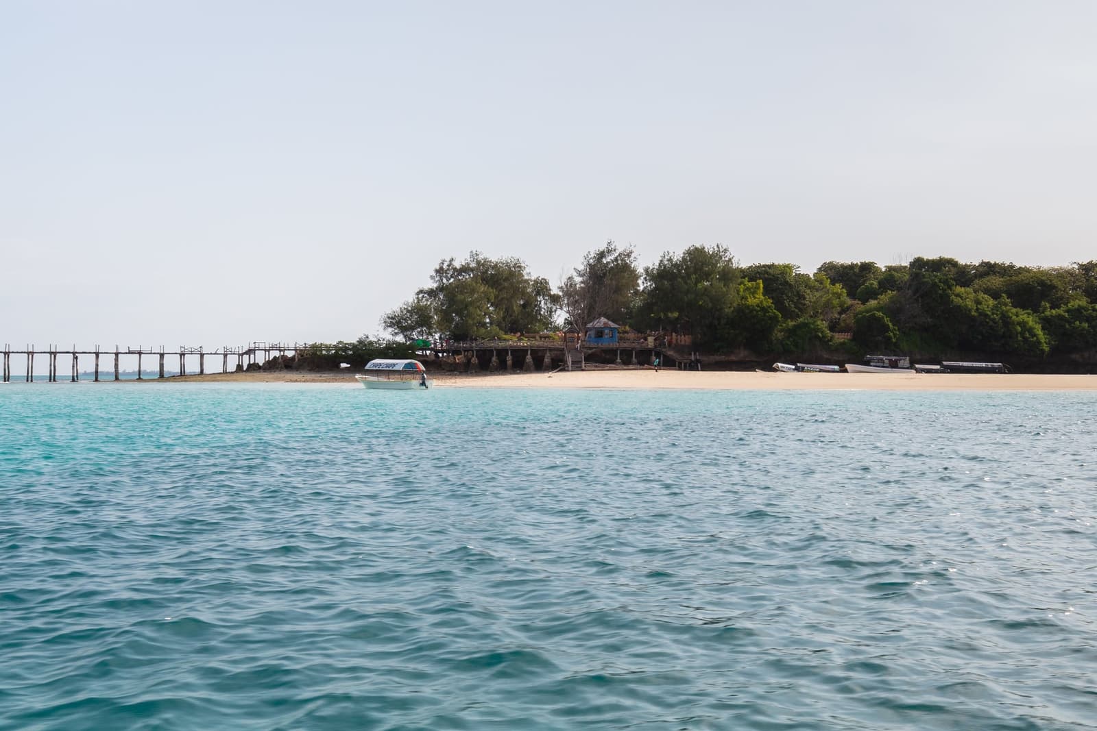 Prison Island seen from the sea with its long wooden jetty and sandy shore